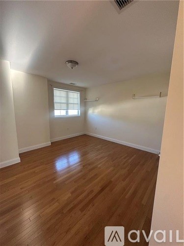 A room with wooden flooring and a window letting in sunlight.
