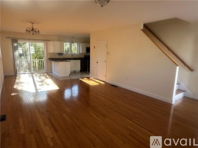 A spacious room with wooden floors and a staircase leading to another level.