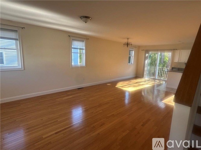 A room with wooden flooring and two windows.