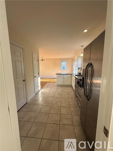 A kitchen with a tiled floor and a refrigerator on the right side.