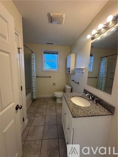 A bathroom with a granite countertop and a window.