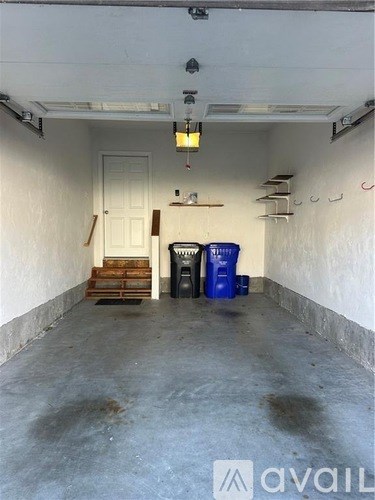 A room with a white door and a blue barrel on the floor.