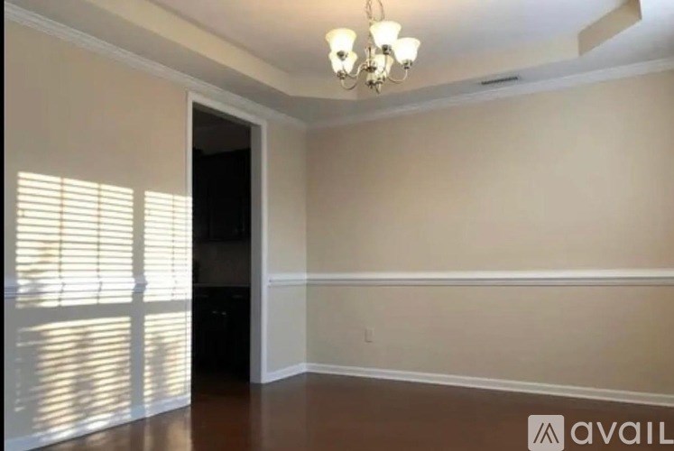A room with a chandelier, a window with blinds, and a door.