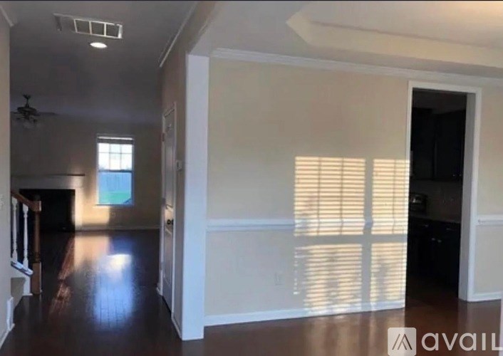 A spacious room with wooden floors and a ceiling fan.