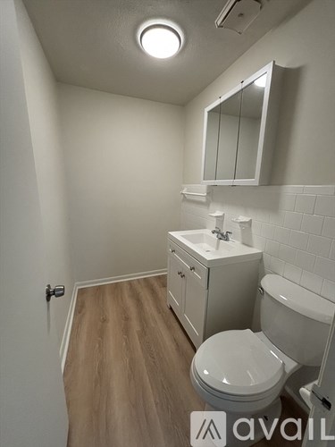 A bathroom with a toilet, sink, and mirror.