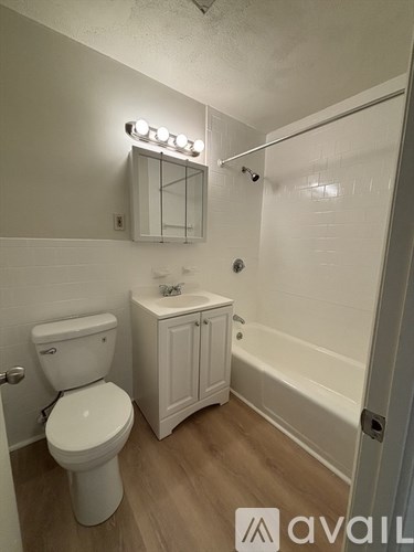 A white toilet is in a small bathroom with a white cabinet and a mirror above it.