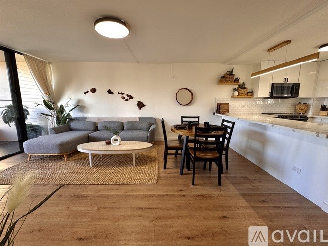 A living room with a grey sofa, a white coffee table, and a dining table with chairs.