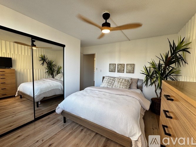 A bedroom with a large bed, a ceiling fan, and a mirrored closet door.