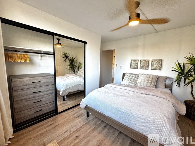 A bedroom with a large bed, a mirror, and a ceiling fan.