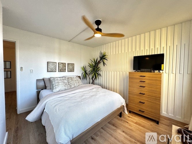 A bedroom with a bed, a TV, and a plant.