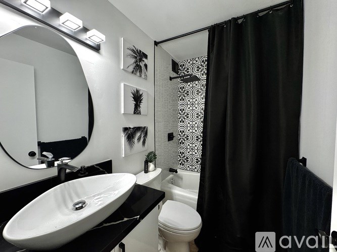 A bathroom with a black sink and a black shower curtain.