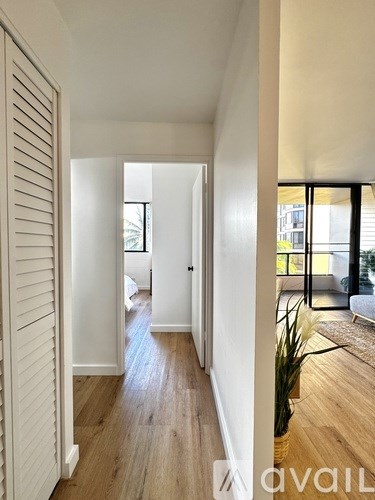 A hallway with wooden floors and white walls leading to a balcony.