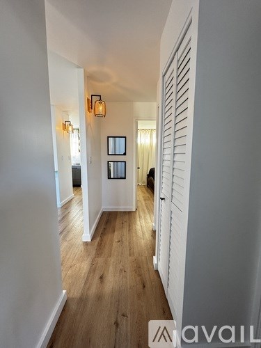 A hallway with wooden floors and white walls.