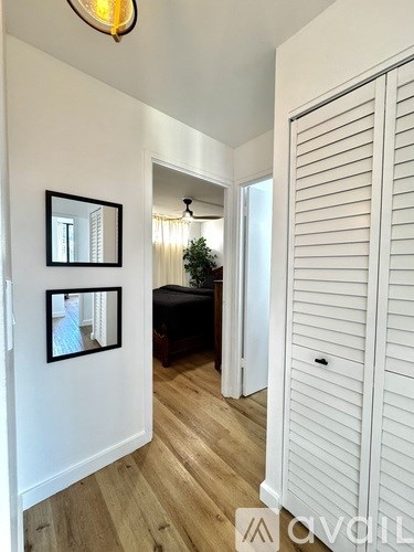A hallway with a white door and two framed mirrors on the wall.