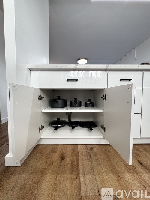 A kitchen with a white cabinet and a wooden floor.