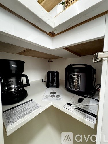 A kitchen with a black coffee maker and a black toaster on a white counter.