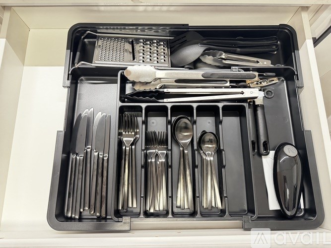 A set of silverware is organized in a black tray.