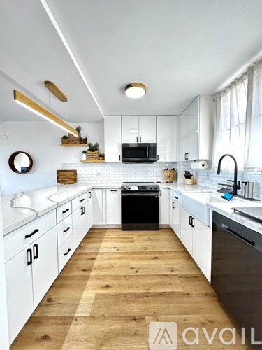 A modern kitchen with white cabinets and wooden flooring.