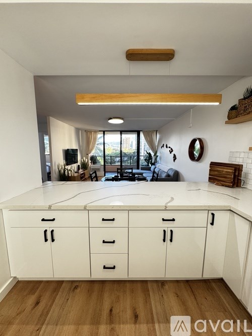 A kitchen with white cabinets and a wooden floor.