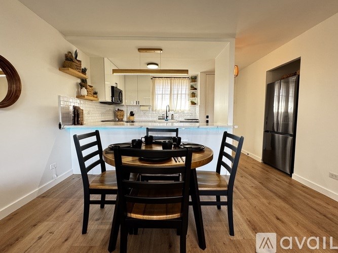 A kitchen with a table and chairs in the foreground and a refrigerator in the background.