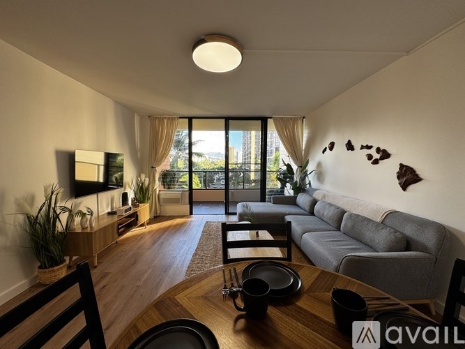 A living room with a grey couch, wooden coffee table, and a large window with a view of the city.