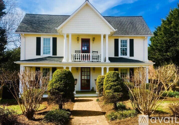 A white house with a red door and black shutters.