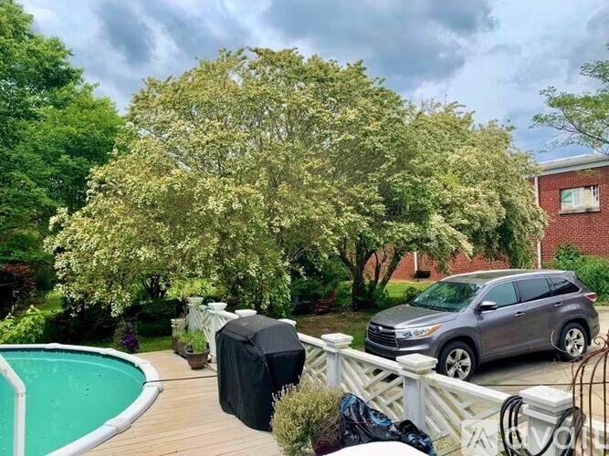 A silver car is parked on a wooden deck next to a pool.