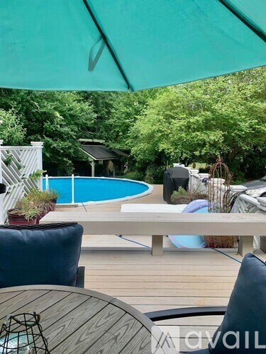 A pool area with a table and chairs under an umbrella.