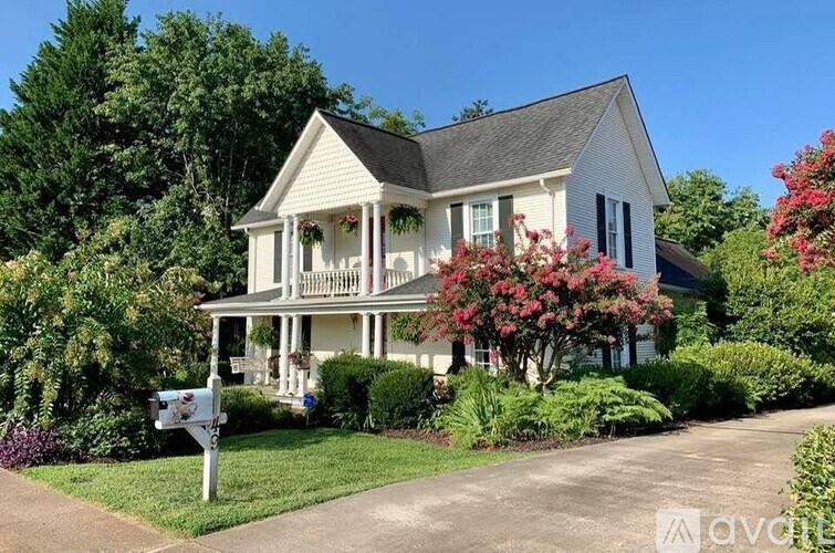 A white house with a black roof and a mailbox in front.