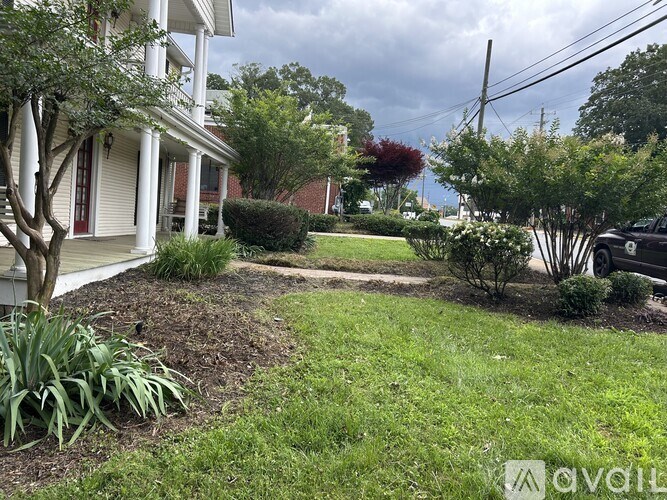 A residential area with a house, trees, and a car parked on the street.