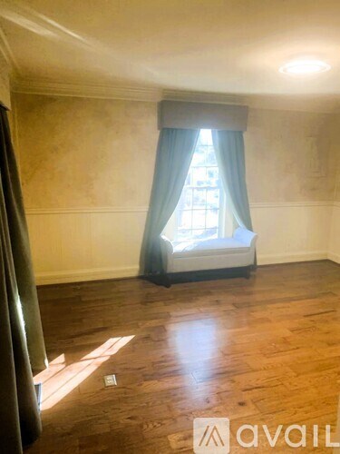 A room with wooden floors and a window with blue curtains.