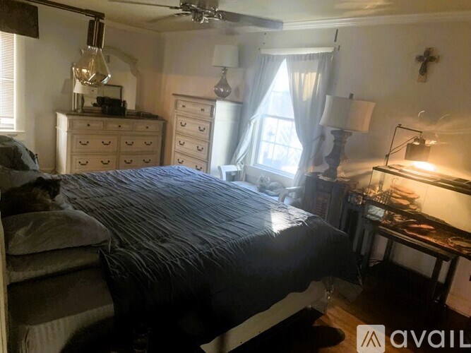 A bedroom with a bed, dresser, and window.