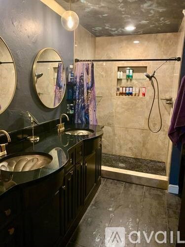 A bathroom with a black countertop and a shower area.