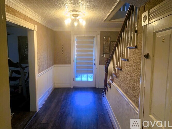 A hallway with a staircase and a door at the end.