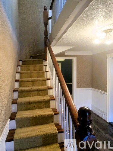A staircase with a beige carpeted runner and wooden banister.