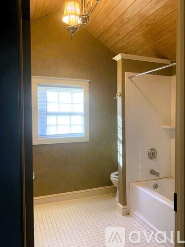 A bathroom with a wooden ceiling and a white bathtub.