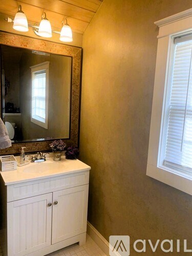 A bathroom with a white vanity and a mirror above it.