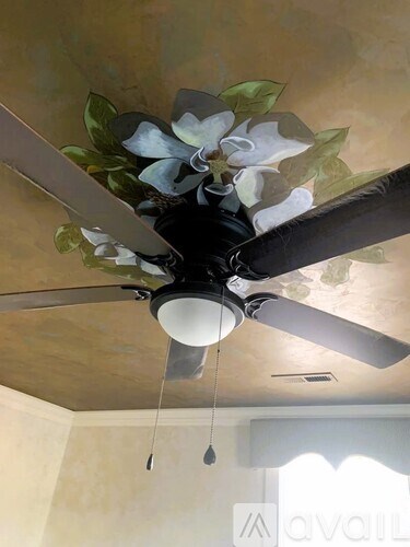 A ceiling fan with a flower design on the blades.