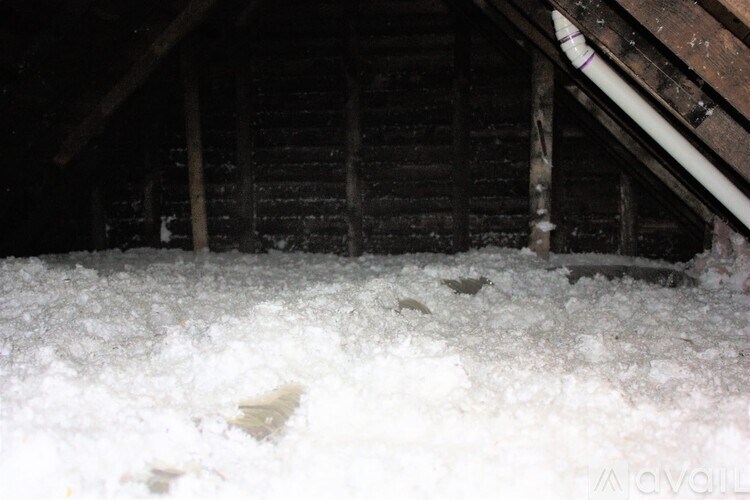 A dark attic with snow on the floor.