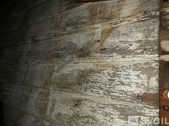 A close up of a weathered wooden wall with peeling paint.
