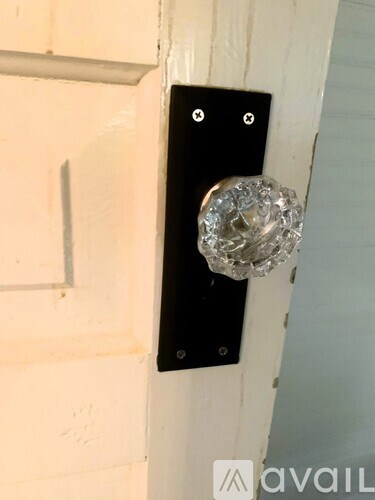 A door handle with a glass knob is mounted on a white door.