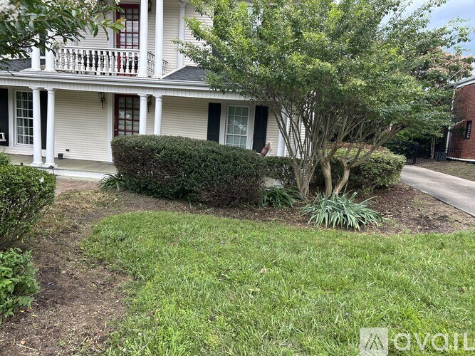 A white house with a red door and a tree in front.