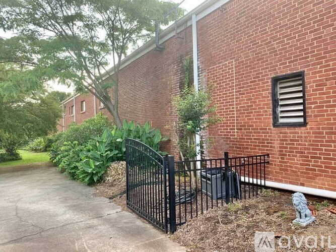 A red brick building with a black gate and a small statue in front.