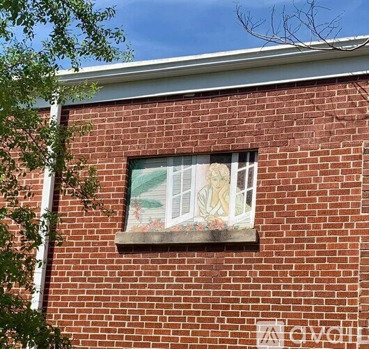 A brick building with a window that has a painting of a woman on it.