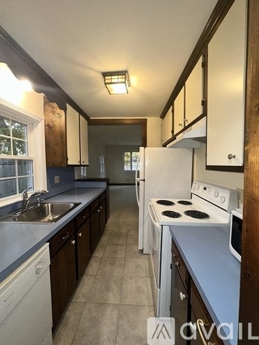 A kitchen with white appliances and wooden cabinets.