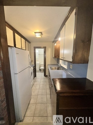 A kitchen with white appliances and brown cabinets.