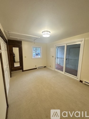 A room with a carpeted floor and a window with blinds.