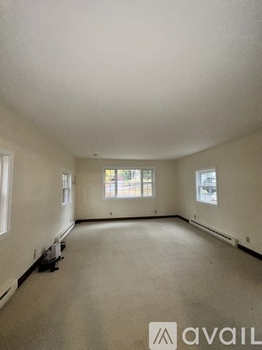 A large empty room with a window and a carpeted floor.