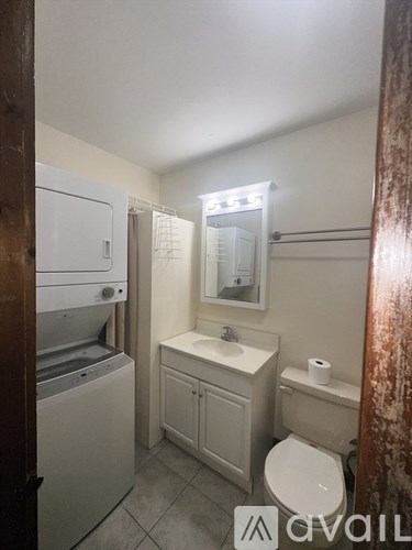 A small bathroom with a toilet, sink, and a washer and dryer.