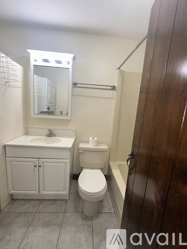 A bathroom with a toilet, sink, and mirror.